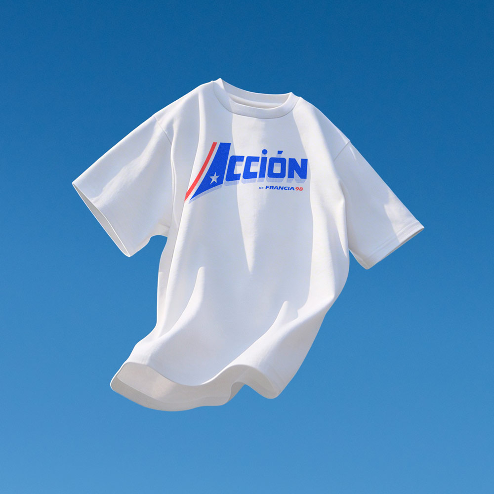 Camiseta Acción de Francia 98 – Volver a Primera Camiseta blanca con ilustración tipográfica “Acción de Francia 98” en colores rojo y azul sobre fondo azul