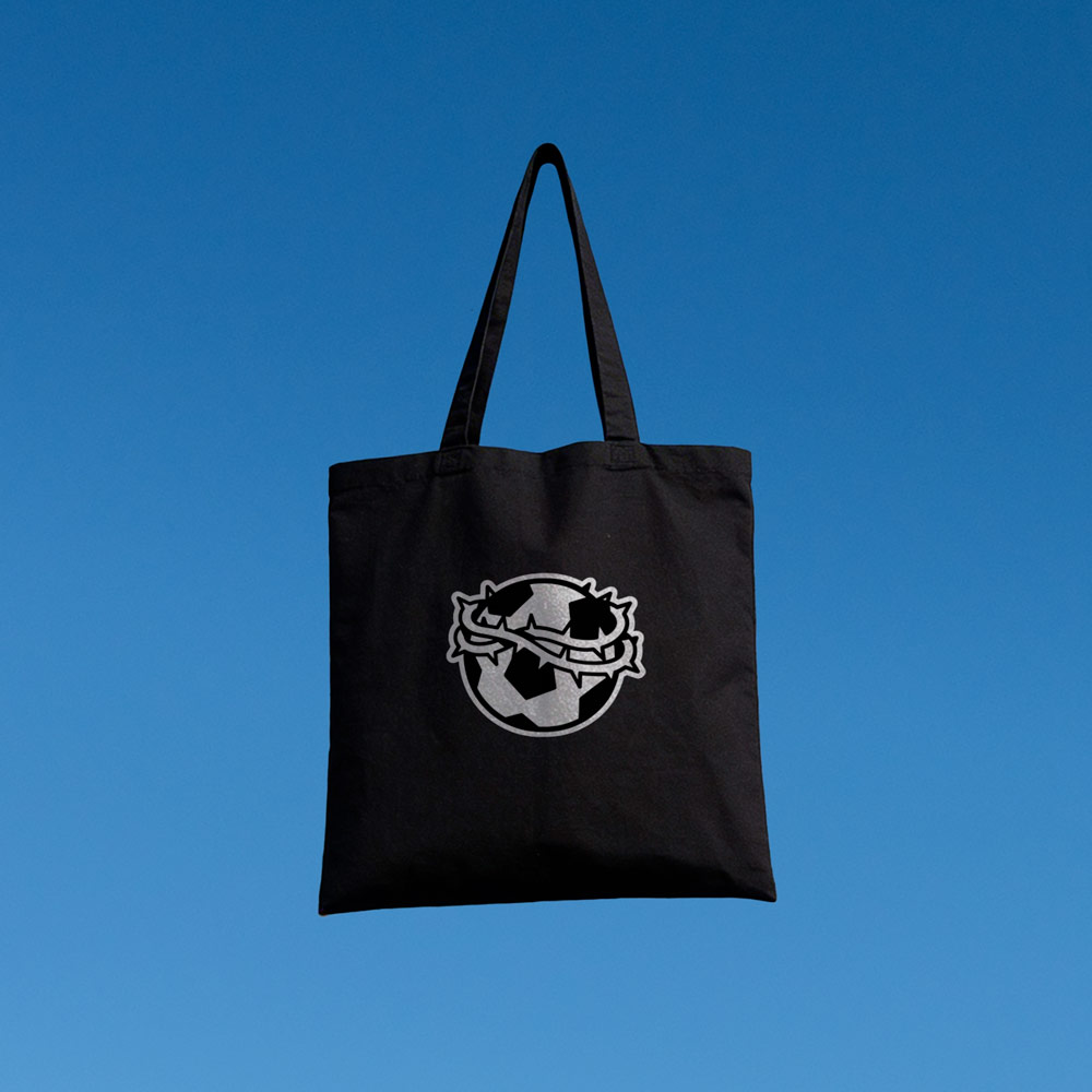 Tote bag Mal de amor – Volver a Primera Tote bag negra Mal de amor de Volver a Primera con balón y corona de espinas